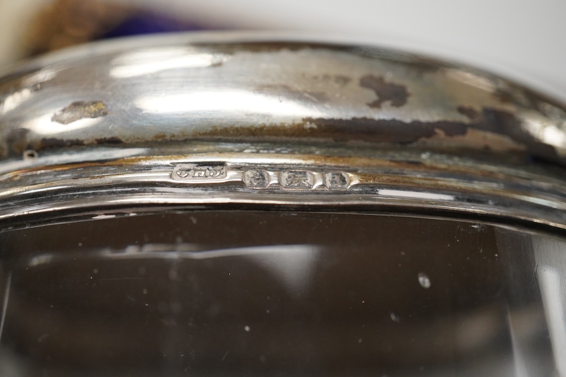 An early 20th century silver mounted cut glass scent bottle, five silver mounted glass toilet jars, a pair of silver mounted dwarf candlesticks, two silver condiments, a sterling jug(weighted), a sterling cup and cover(w